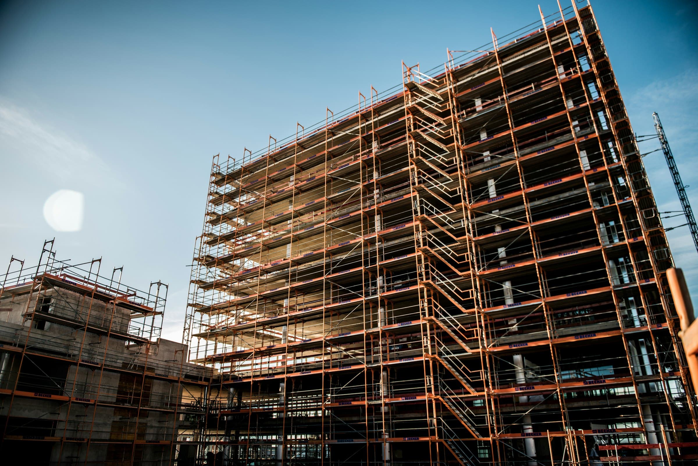 Eingerüsteter Neubau mit mehreren Gerüstlagen im Abendlicht