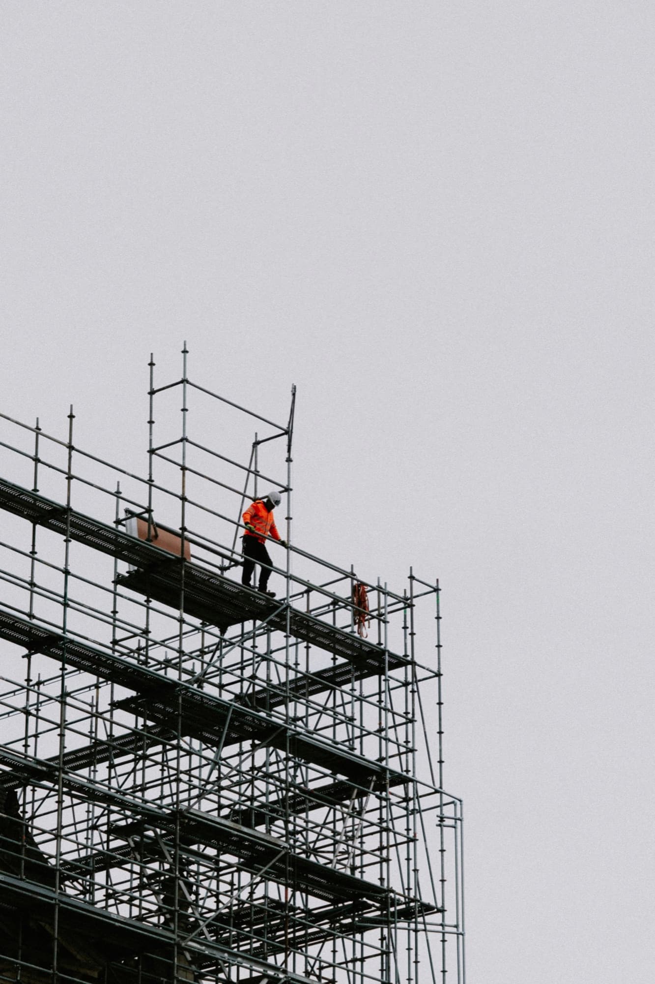 Gerüstbauer auf der obersten Gerüstlage vor grauem Himmel